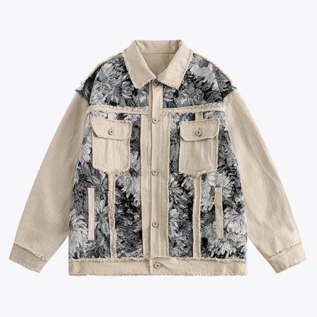 Close-up of a beige denim jacket with a black flower-patterned design and frayed edges on the shoulders and chest pockets
