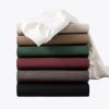 a neatly stacked collection of crew neck t-shirts in different colors, including white, red, green, brown, and black, showcasing the fabric's texture and variety.