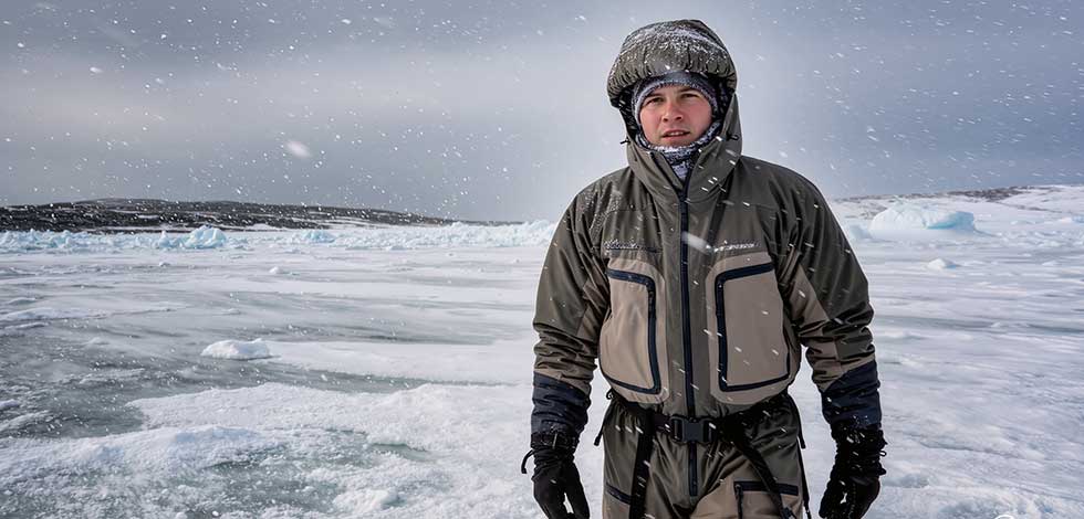 A person testing outdoor apparel in snowy, icy conditions during a real-world simulation of extreme weather