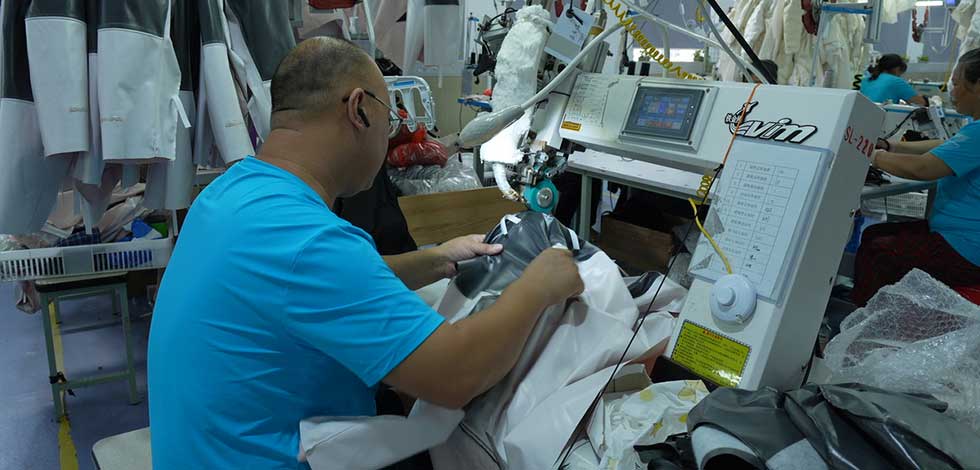 A worker sewing and assembling outdoor jackets designed for extreme conditions in a factory setting