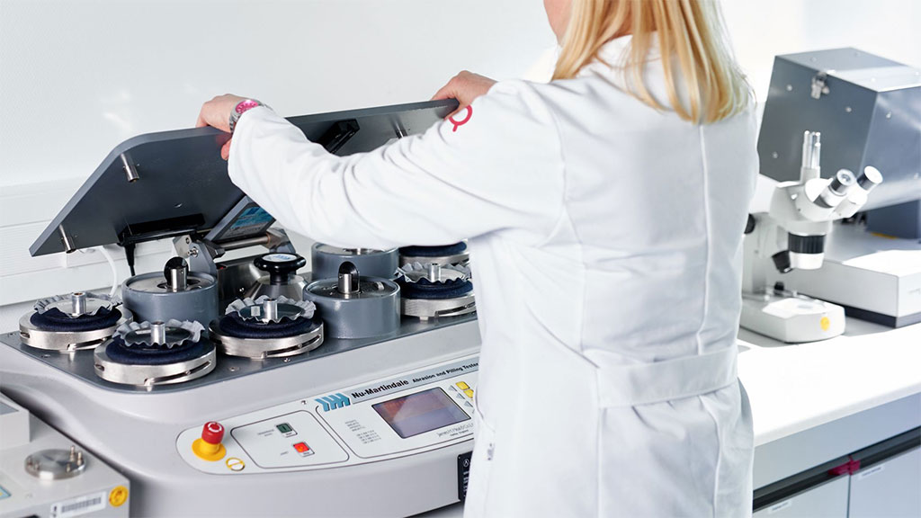 Lab technician testing textile samples on multi-station fabric testing machine.