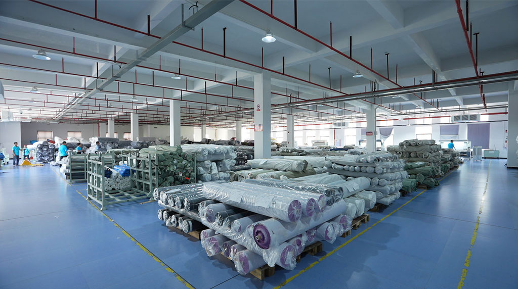 Factory workers handling bulk fabric rolls for production.