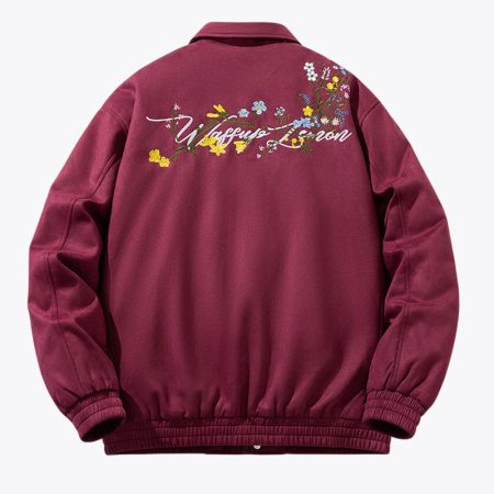 A back-facing studio product shot of the Burgundy Simmerui baseball jacket featuring a structured collar, intricate colorful floral embroidery on the right shoulder and left chest, and ribbed cuffs and hem.