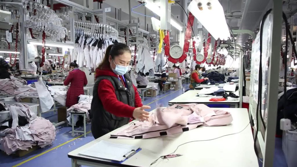 Garment inspector checking apparel on a production line representing inline quality control during bulk manufacturing