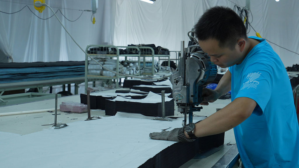 Worker operating fabric cutting equipment representing precision cutting in apparel production