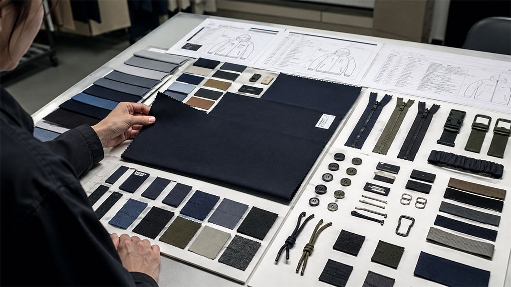 A detailed view of fabric swatches and trim components (zippers, buttons, buckles) laid out for approval. Confirming materials before sampling ensures the final garment matches your design vision and prevents costly revisions.