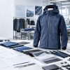 Outdoor apparel development and OEM manufacturing setup featuring a technical jacket, fabric swatches, tech packs, zippers and trims for prototype sampling and production.