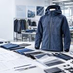 Outdoor apparel development and OEM manufacturing setup featuring a technical jacket, fabric swatches, tech packs, zippers and trims for prototype sampling and production.